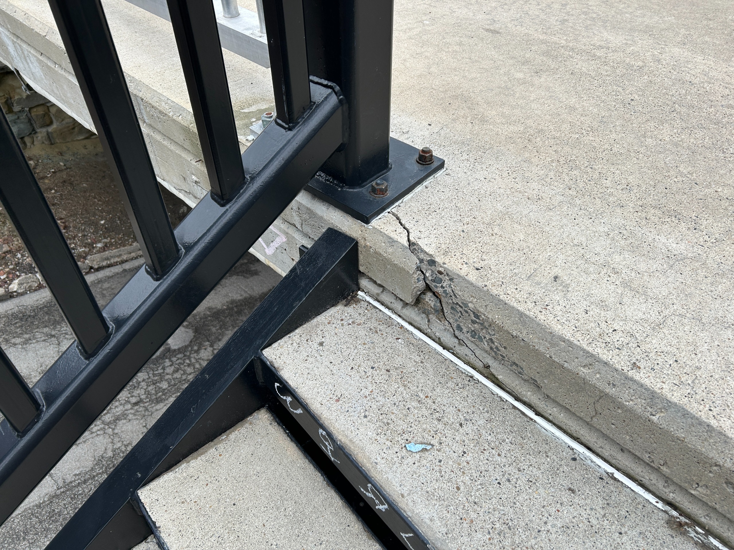 Spalled concrete at stair railing baseplate.